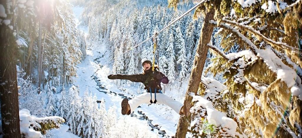 Person ziplining through a snow-covered forest in Whistler.