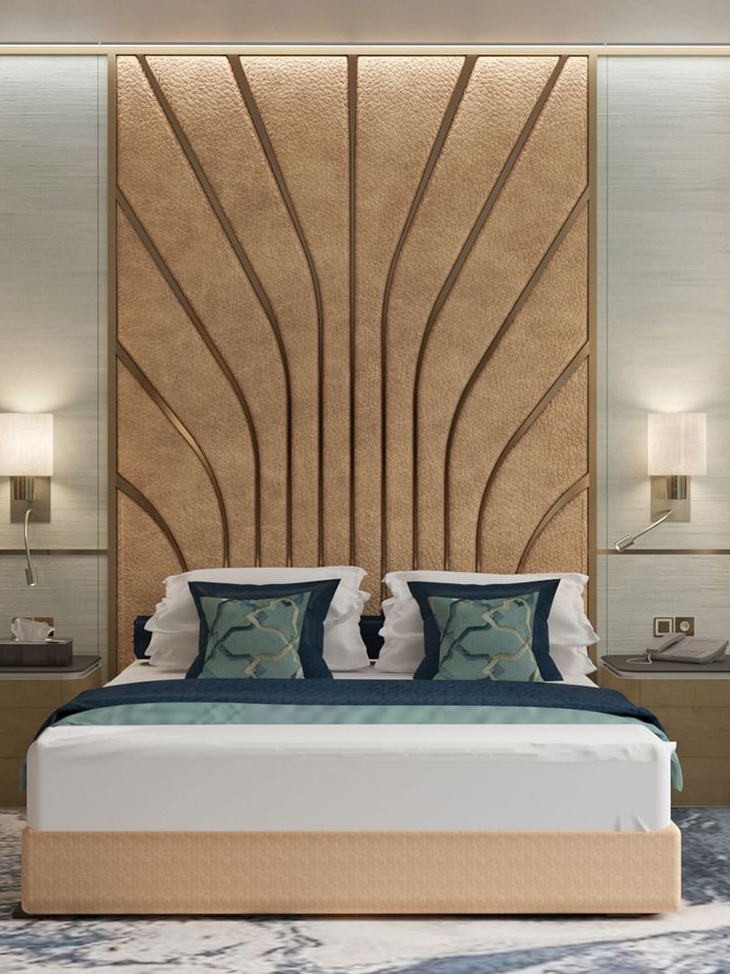Modern bed with a patterned headboard by a blue chair in the Ambassador Suite at Cantonal Hotel by Warwick Riyadh