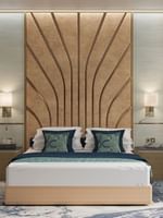 Modern bed with a patterned headboard by a blue chair in the Ambassador Suite at Cantonal Hotel by Warwick Riyadh