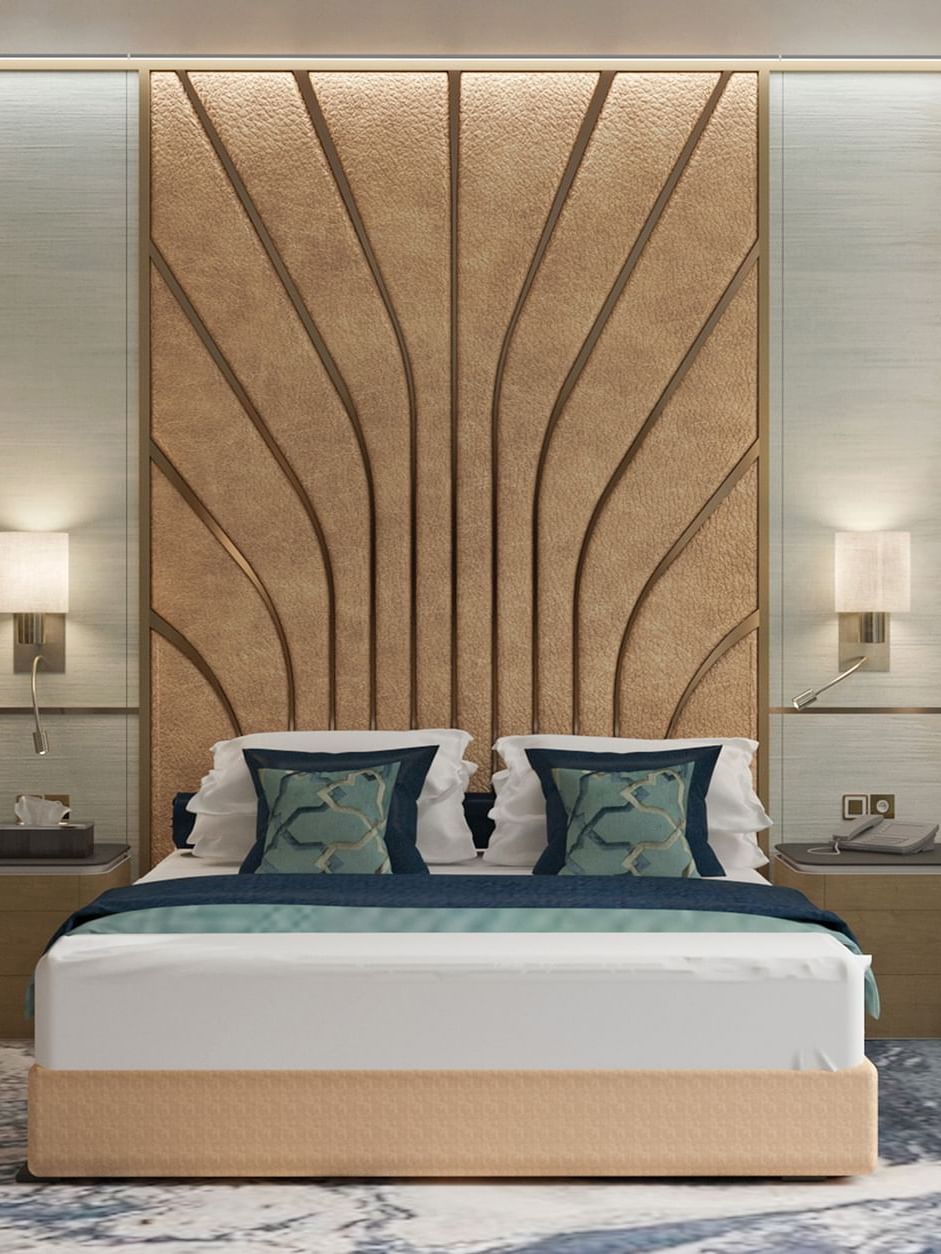 Modern bed with a patterned headboard by a blue chair in the Ambassador Suite at Cantonal Hotel by Warwick Riyadh
