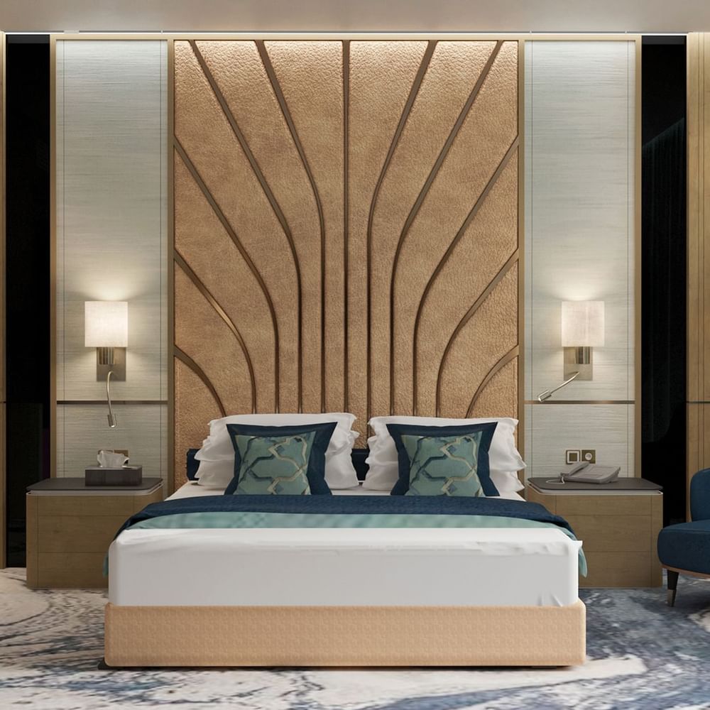Modern bed with a patterned headboard by a blue chair in the Ambassador Suite at Cantonal Hotel by Warwick Riyadh