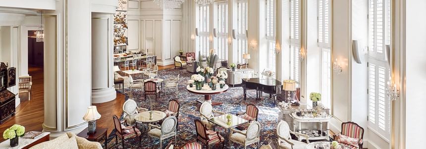 Dining area with a grand chandelier, ornate furniture, and large windows in Park Lounge at Park Hyatt Saigon
