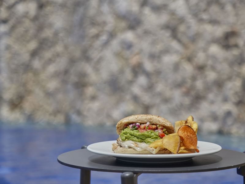 A burger dish served with potato chips at FA Hotels & Resorts