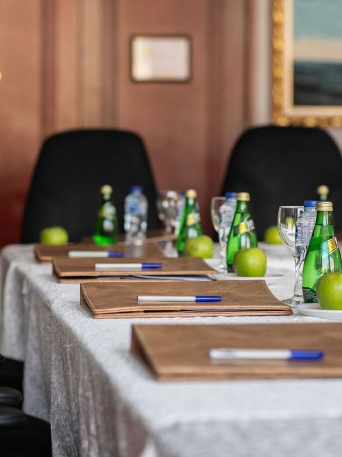 Close-up of a meeting table featuring leather folders and water bottles by black chairs in Al Khaleej at Warwick Al Jubail