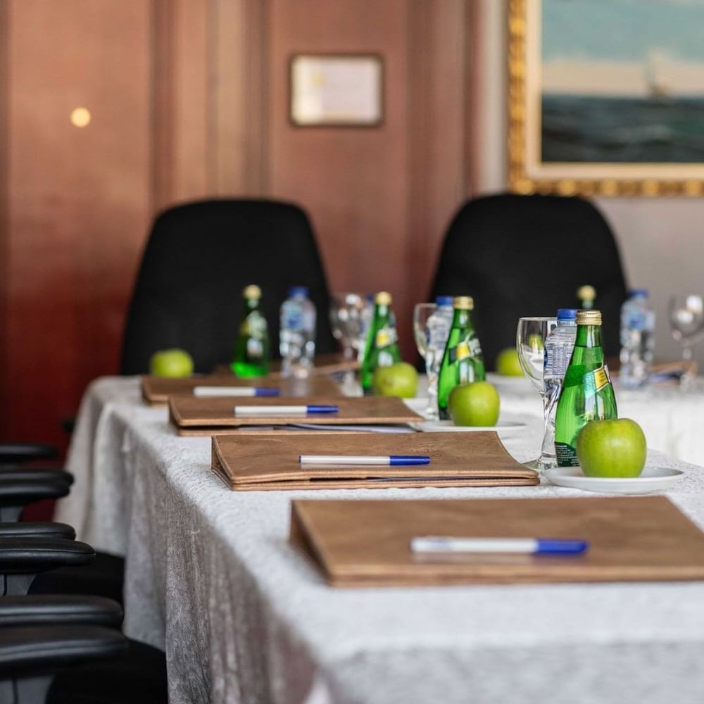 Close-up of a meeting table featuring leather folders and water bottles by black chairs in Al Khaleej at Warwick Al Jubail