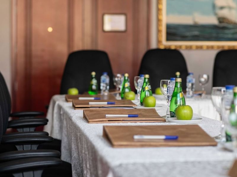 Close-up of a meeting table featuring leather folders and water bottles by black chairs in Al Khaleej at Warwick Al Jubail