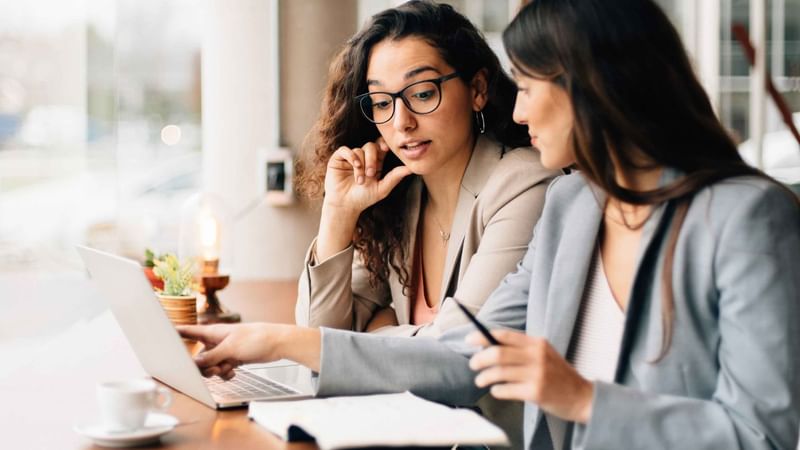Two individuals working on a laptop and taking notes at a table in Mercure Kooindah Waters