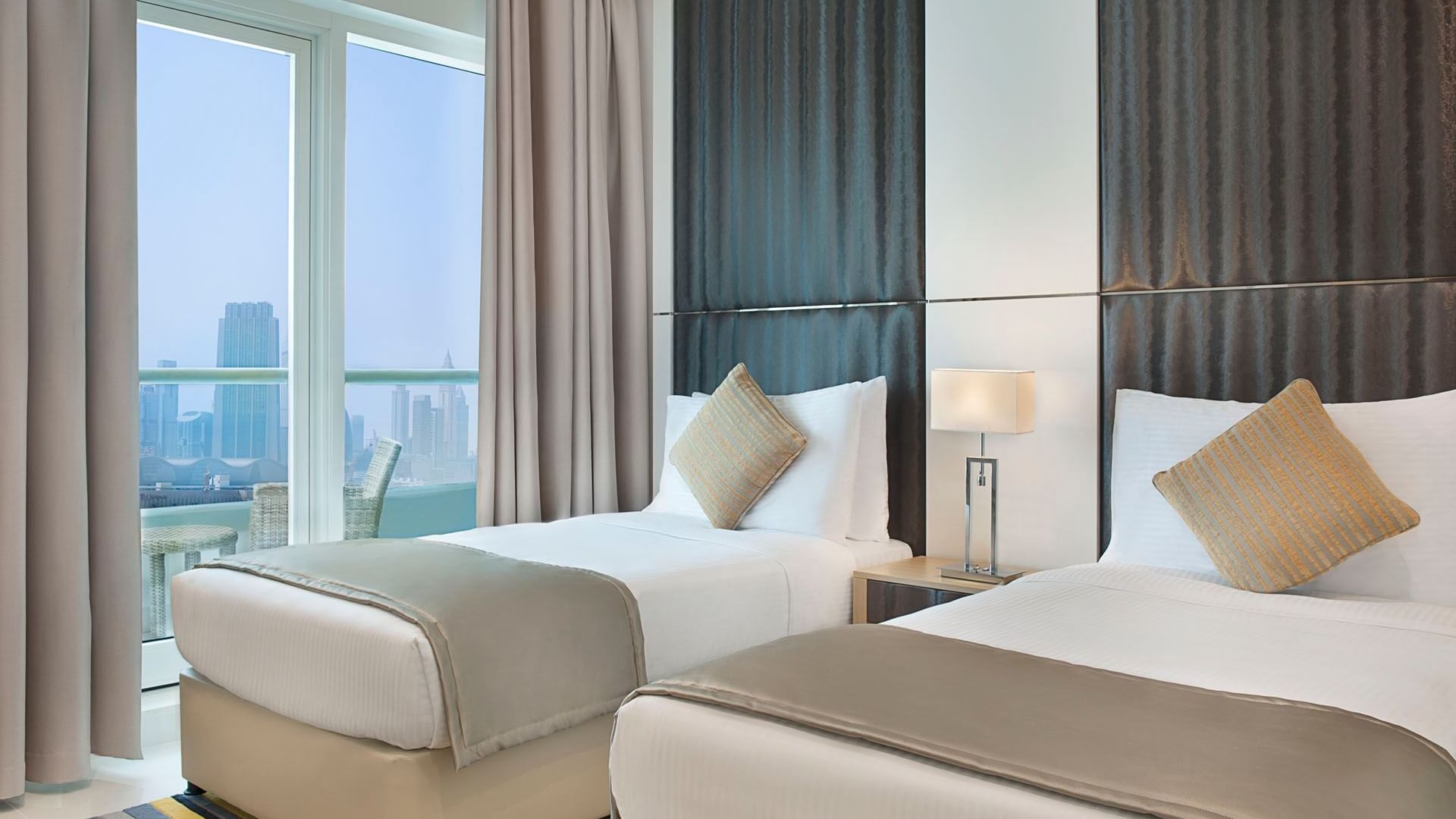 Twin beds and private balcony with city view in Two Bedroom Suite at DAMAC Maison Canal Views