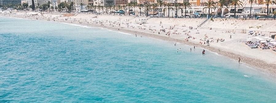 Vibrant beach with clear blue waters and crowds enjoying the shore near Novotel Sydney International Airport