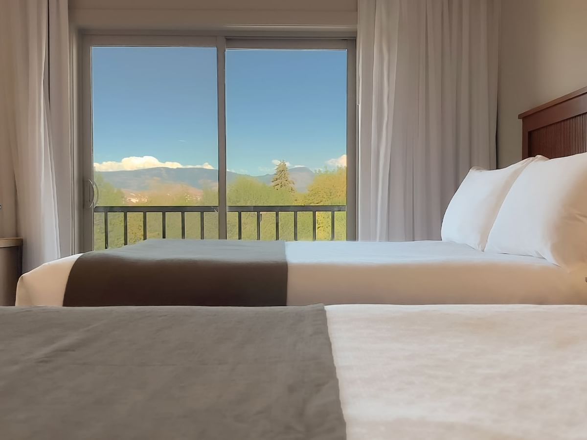 Guest room with two queen beds, balcony chair and desk