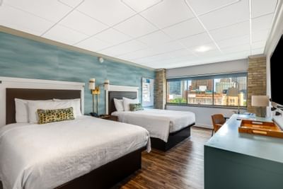 Bright Double Queen Pool View at The Riverwalk Plaza Hotel with two beds, a modern desk, and a wooden chair by the window