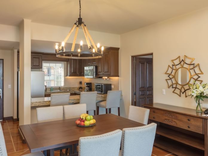 Stylish dining room with a wooden table and open kitchen with counters in Two Bedroom Villa at Hacienda Del Mar Los Cabos.