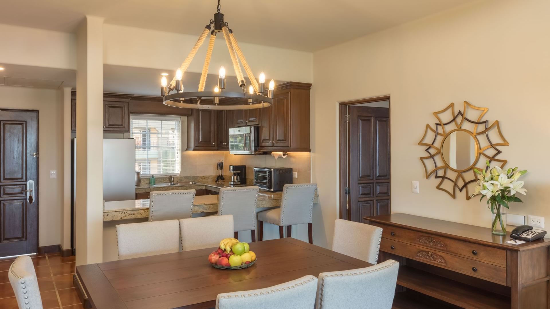 Stylish dining room with a wooden table and open kitchen with counters in Two Bedroom Villa at Hacienda Del Mar Los Cabos.