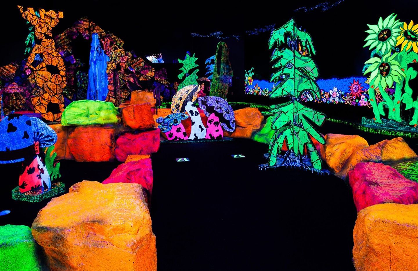 A glow in the dark mini golf course with bright neon colors.