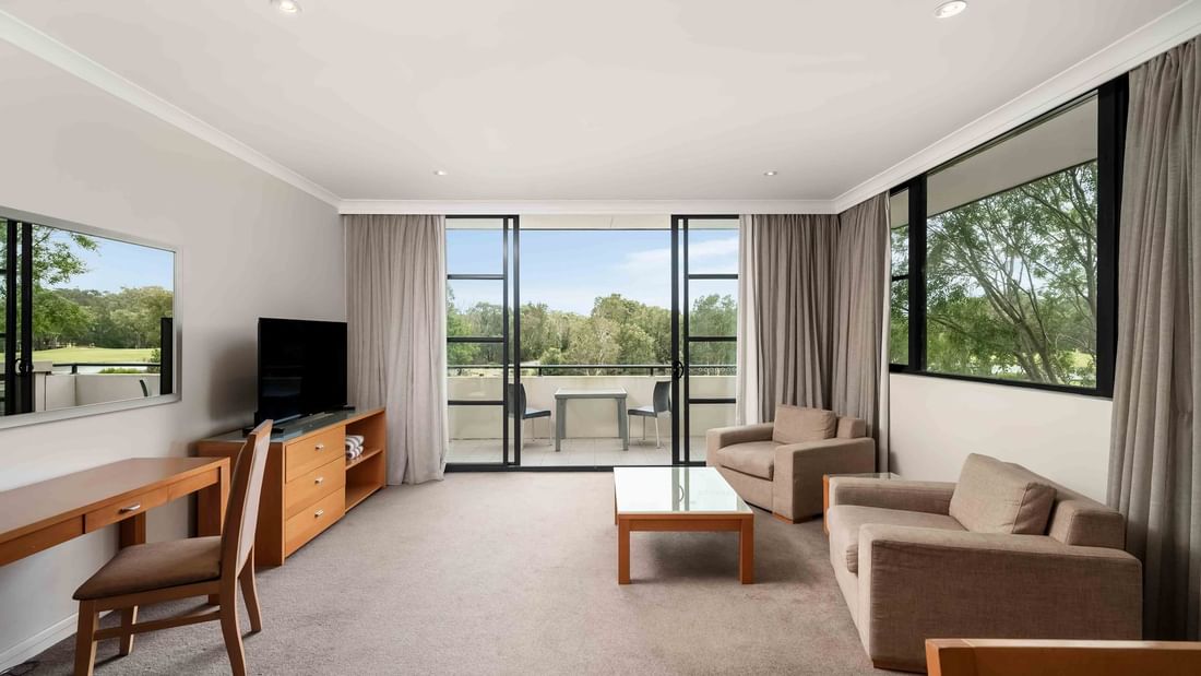 Privilege Room with sofa, desk, TV, and balcony overlooking greenery at Mercure Kooindah Waters