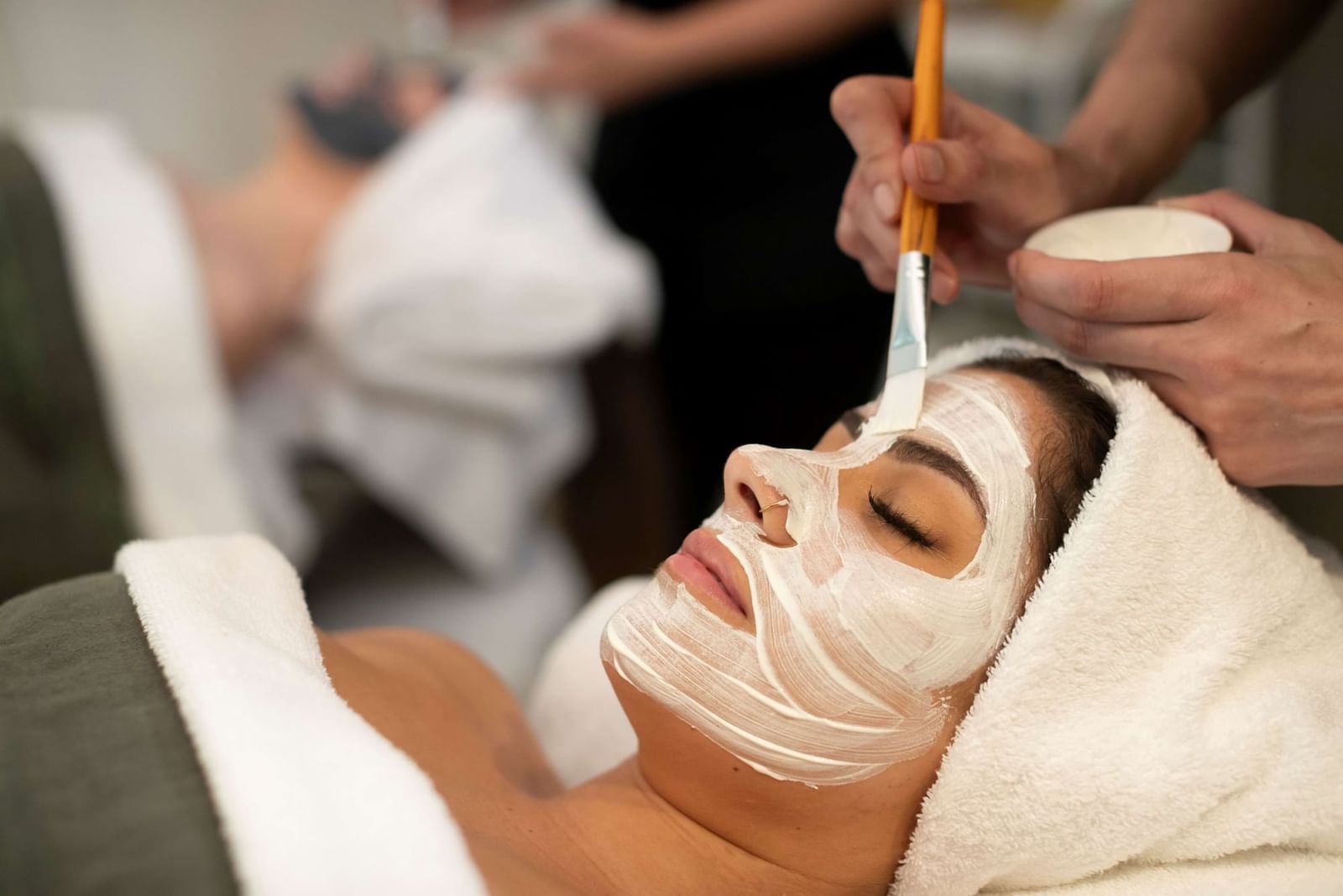 Woman relaxing during a soothing facial treatment at the luxurious Pullman Magenta Shores spa, eyes closed