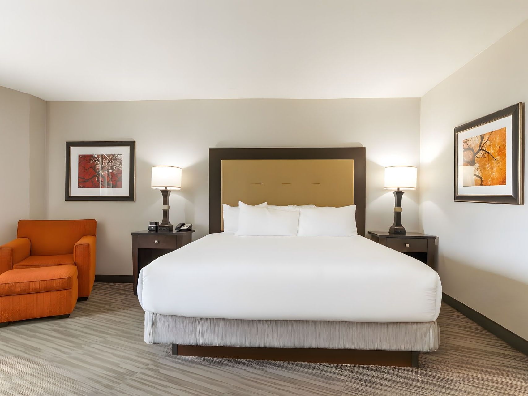 King bed with tan headboard, orange armchair, and warm bedside lamps in Premium King Room at Branson Hillside Hotel