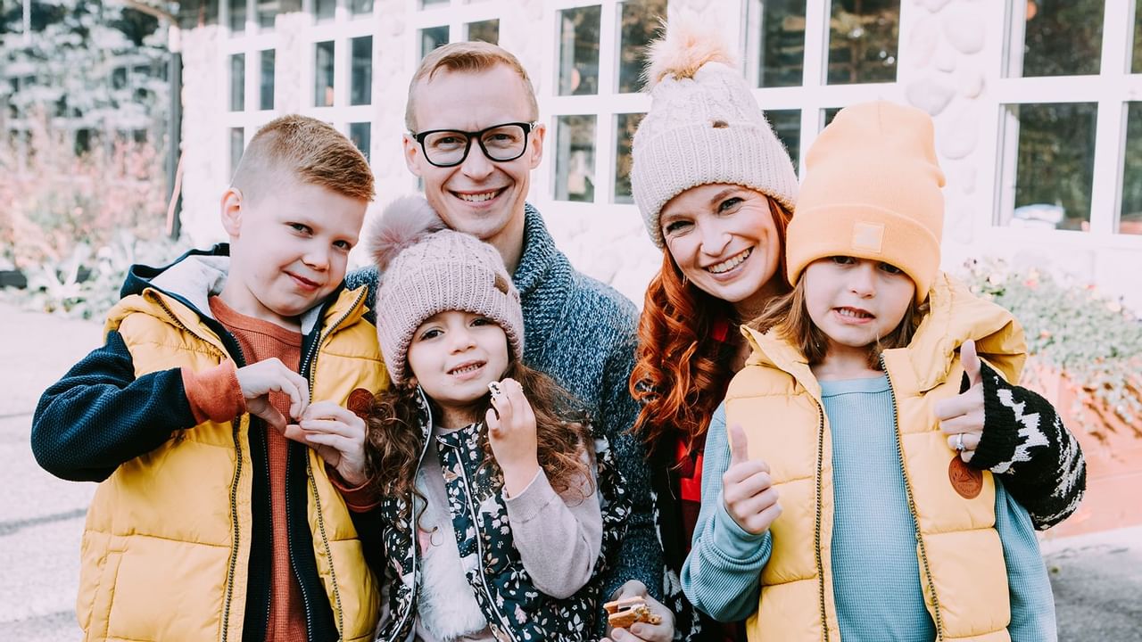 Family of five smiling for a photo wearing winter hats and vest
