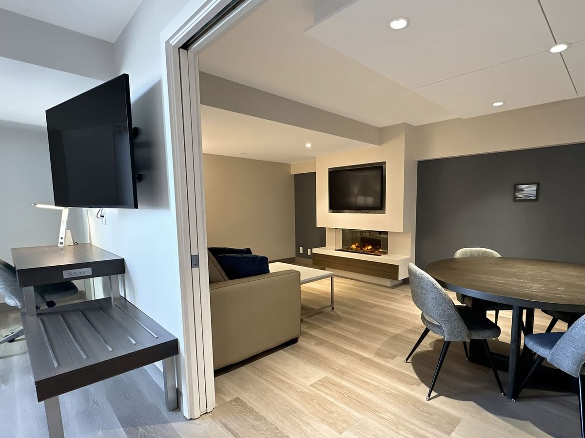 Hotel guestroom with work desk, wall mounted TV, and a round table with chairs