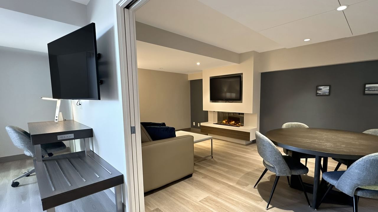 Hotel guestroom with work desk, wall mounted TV, and a round table with chairs
