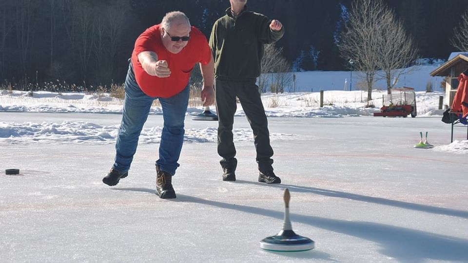 People play curling outside at Liebes Rot Flueh in winter
