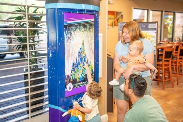 A family gathers around a Walt Disney World kiosk in the lobby of Rosen Inn Lake Buena Vista in Orlando.