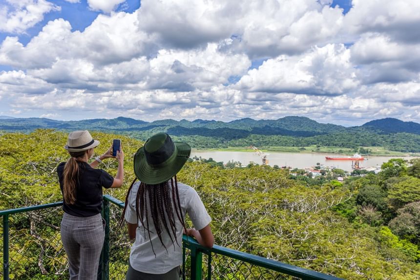Dos mujeres con sombreros toman fotos del paisaje en Gamboa Rainforest Resort.