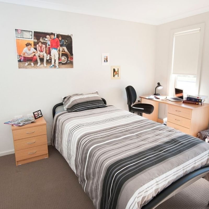 A tidy room with a bed, desk, and two windows at La Trobe University Regional Housing.