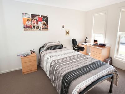 A tidy room with a bed, desk, and two windows at La Trobe University Regional Housing.