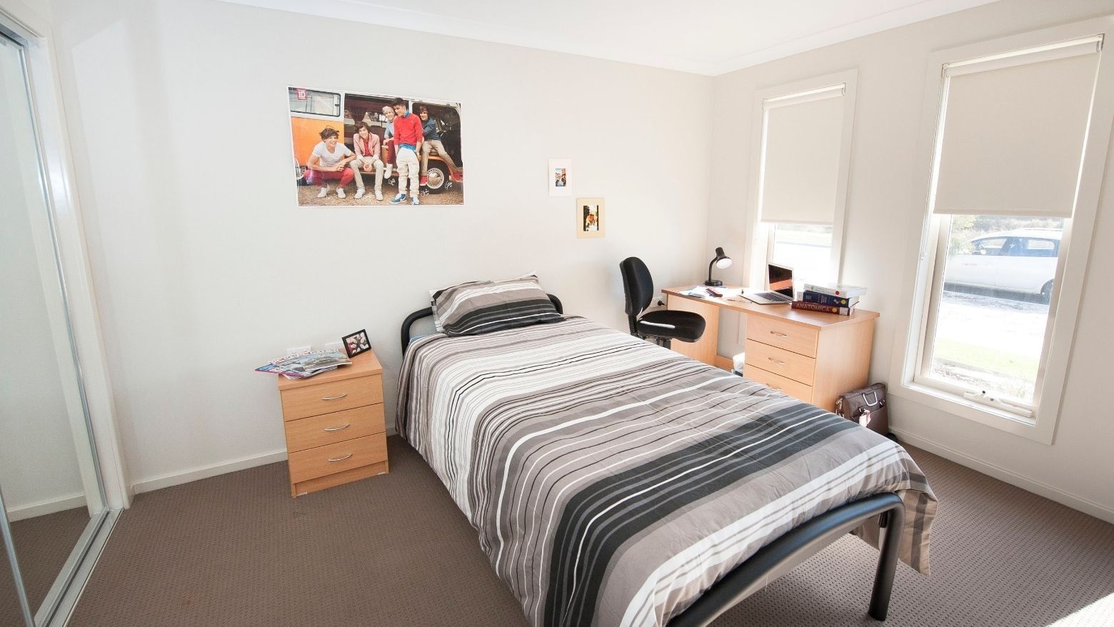 A tidy room with a bed, desk, and two windows at La Trobe University Regional Housing.