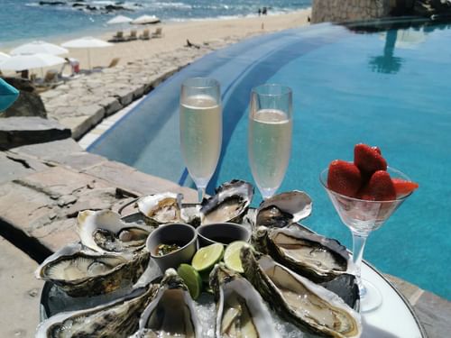 Tray of oysters and champagne by a poolside overlooking the beach in Sirenas Restaurant at Hacienda del Mar Los Cabos.