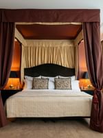 Une chambre élégante avec un lit à baldaquin et une décoration raffinée au Warwick Champs-Élysées à Paris.