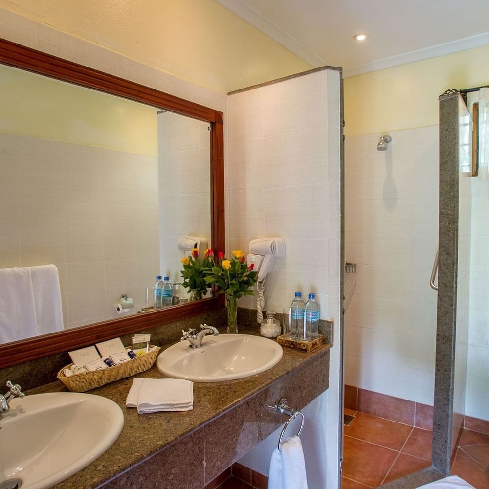 Clean bathroom with two sinks, mirror, and separate toilet stall at Arusha Serena Hotel in Arusha.