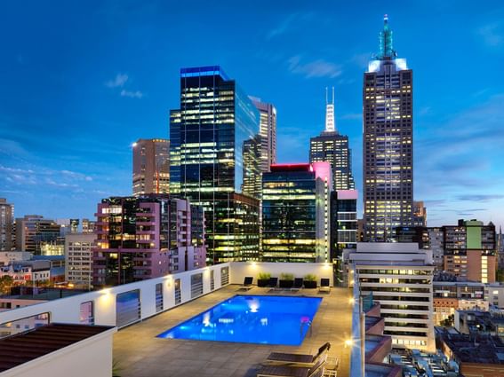 Outdoor pool on rooftop with attractive evening city view at Hotel Grand Chancellor Melbourne