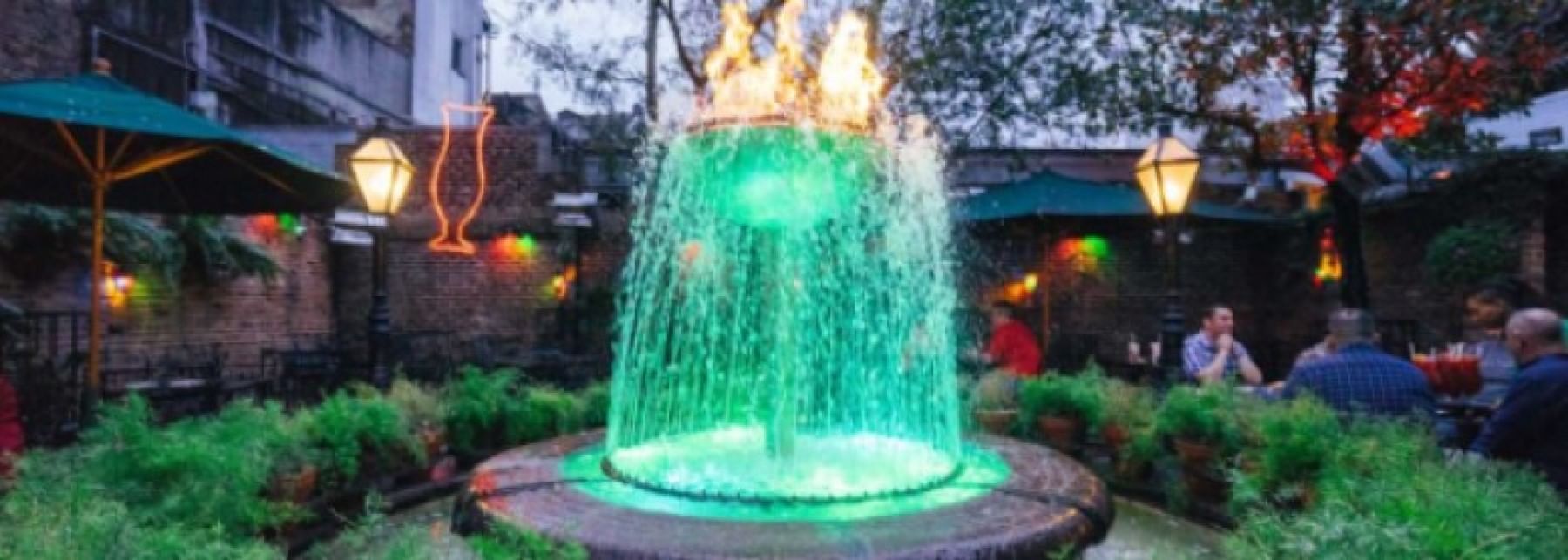 A large outdoor fountain with green water and flames on top