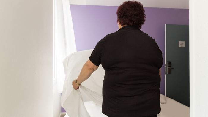 A maid preparing a bed in a room at Hotel Nevers Centre Gare