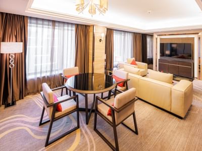 Stylish Executive suite featuring a round table, cream couches, and floor-to-ceiling windows at Grand Emperor Hotel