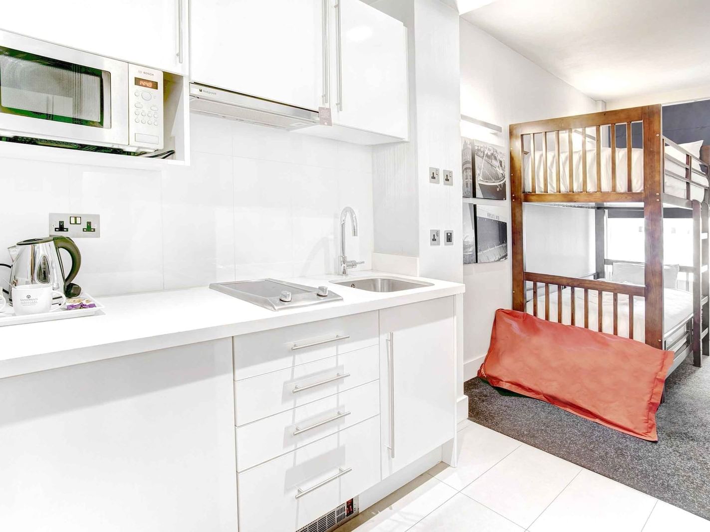 The Family King Suite at Sandman Signature Newcastle Hotel with two bunk beds and a pantry with kitchen supplies and white pantry cupboards