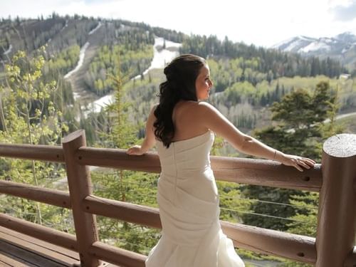 A bride stands at a wooden balcony at Stein Eriksen Lodge