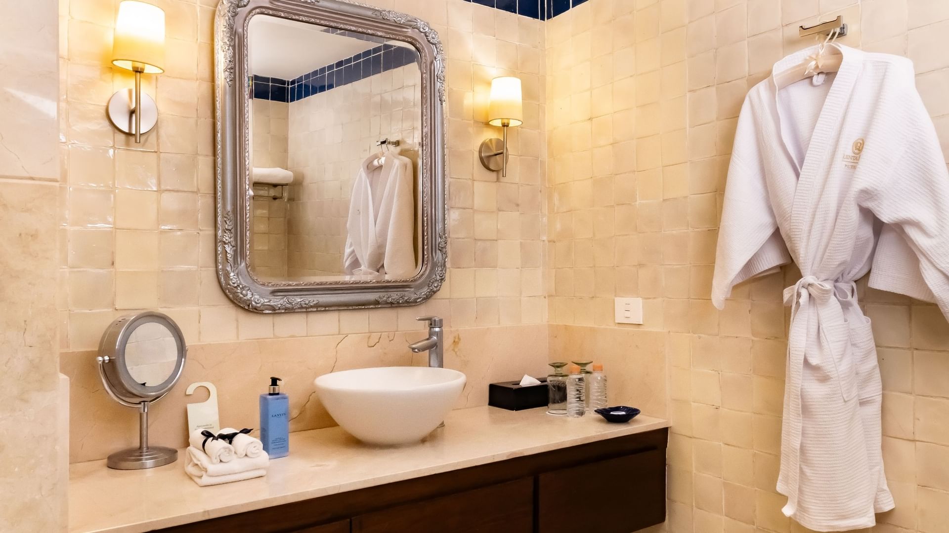 Baño elegante con espejo, lavabo, toallas y albornoz en Suite Gran Clase King en Quinta Real Puebla, Heroica Puebla de Zaragoza.