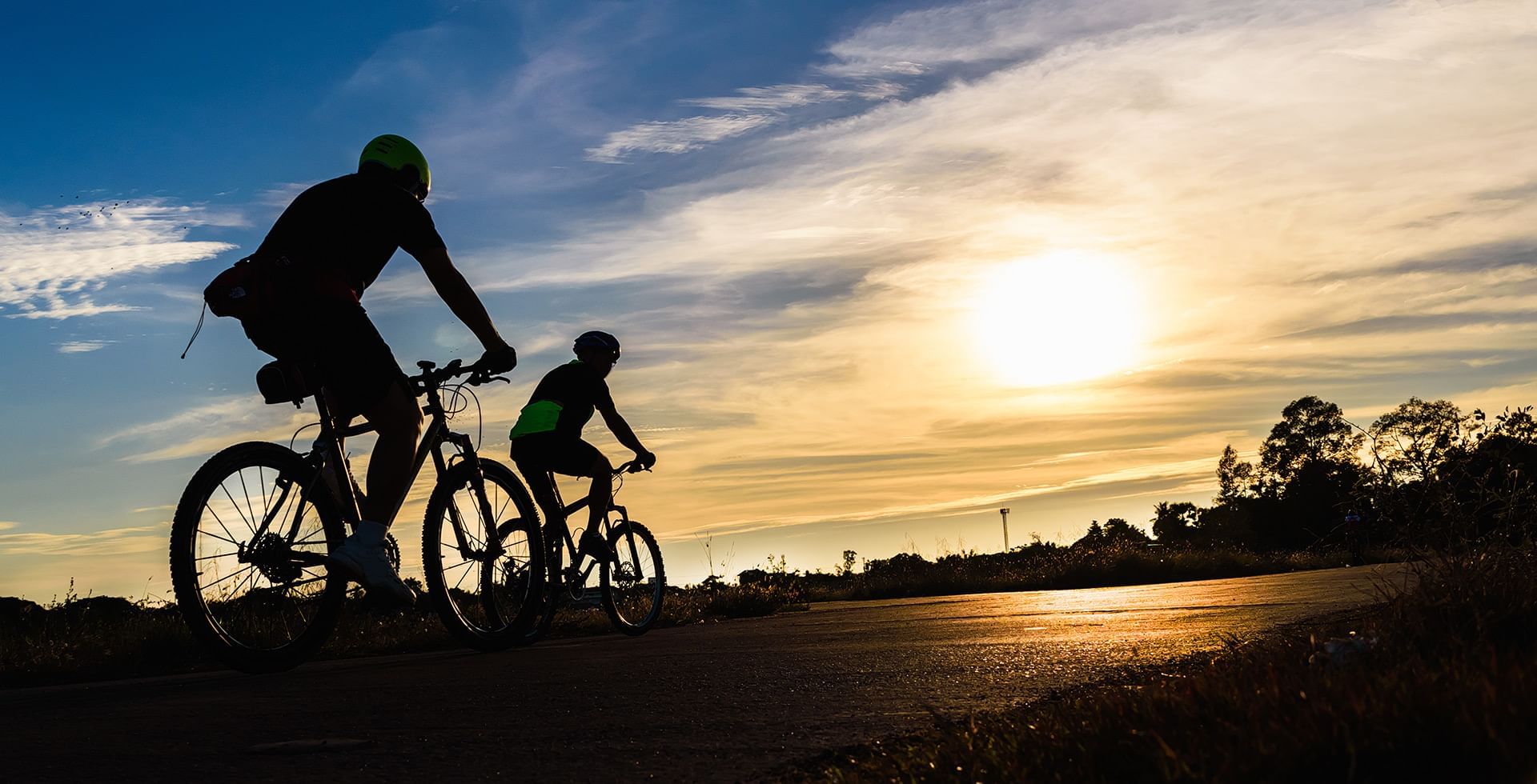Two men riding bicycles at the sunset near Coast Fort St.John