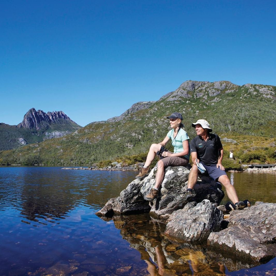 2 men sitting on a rock at dove lake near Cradle Mountain Hotel