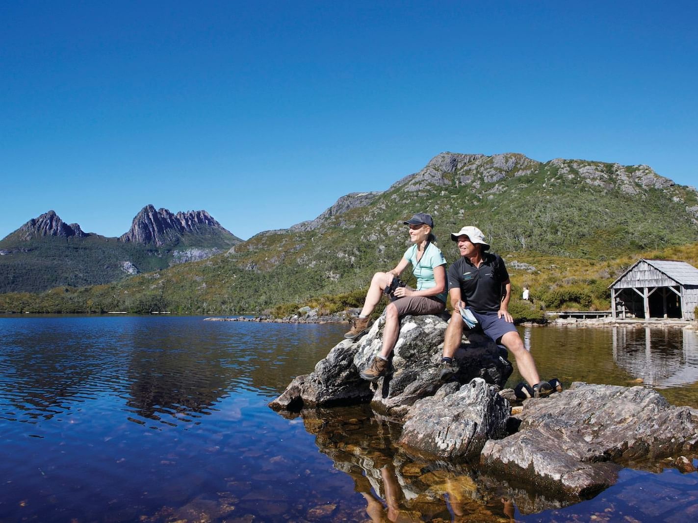 2 men sitting on a rock at dove lake near Cradle Mountain Hotel