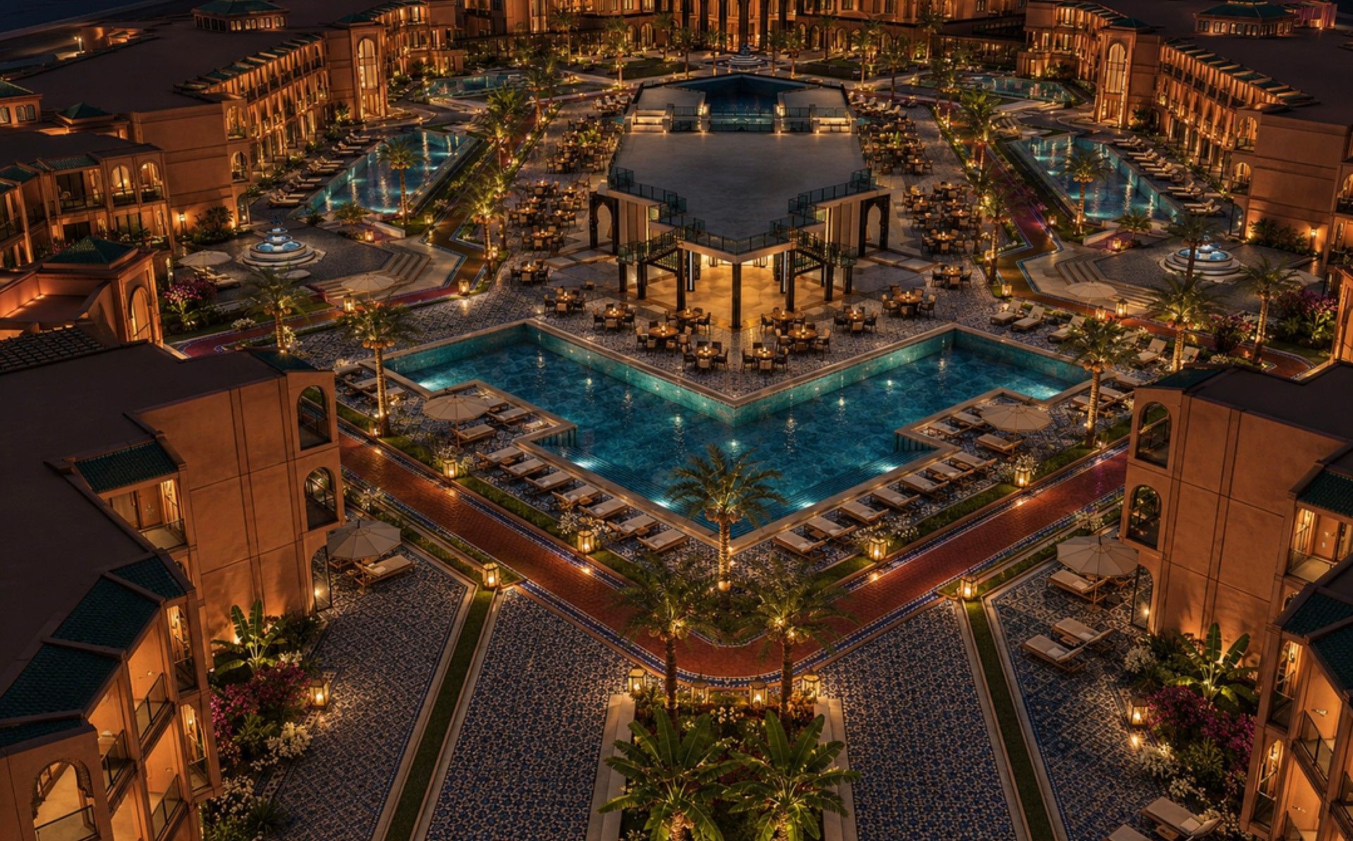 Aerial night view of blue pools by loungers and palm-lined courtyard at Palmeraie Golf Palace by Pickalbatros