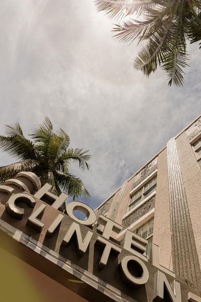 A hotel sign and palm tree against a cloudy sky at Clinton Hotel and Spa