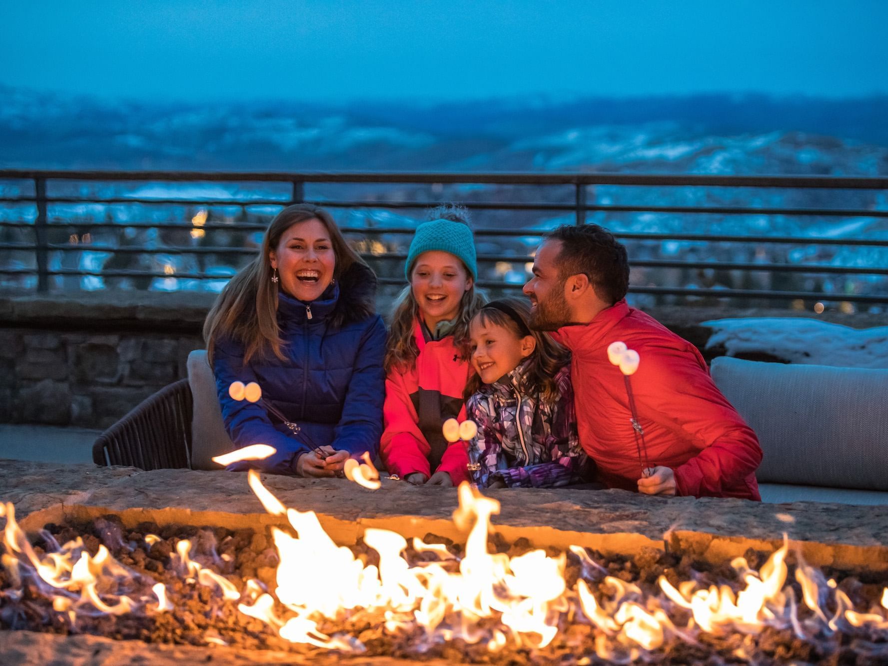 Family roasting hot dogs over fire pit at Stein Eriksen Residences