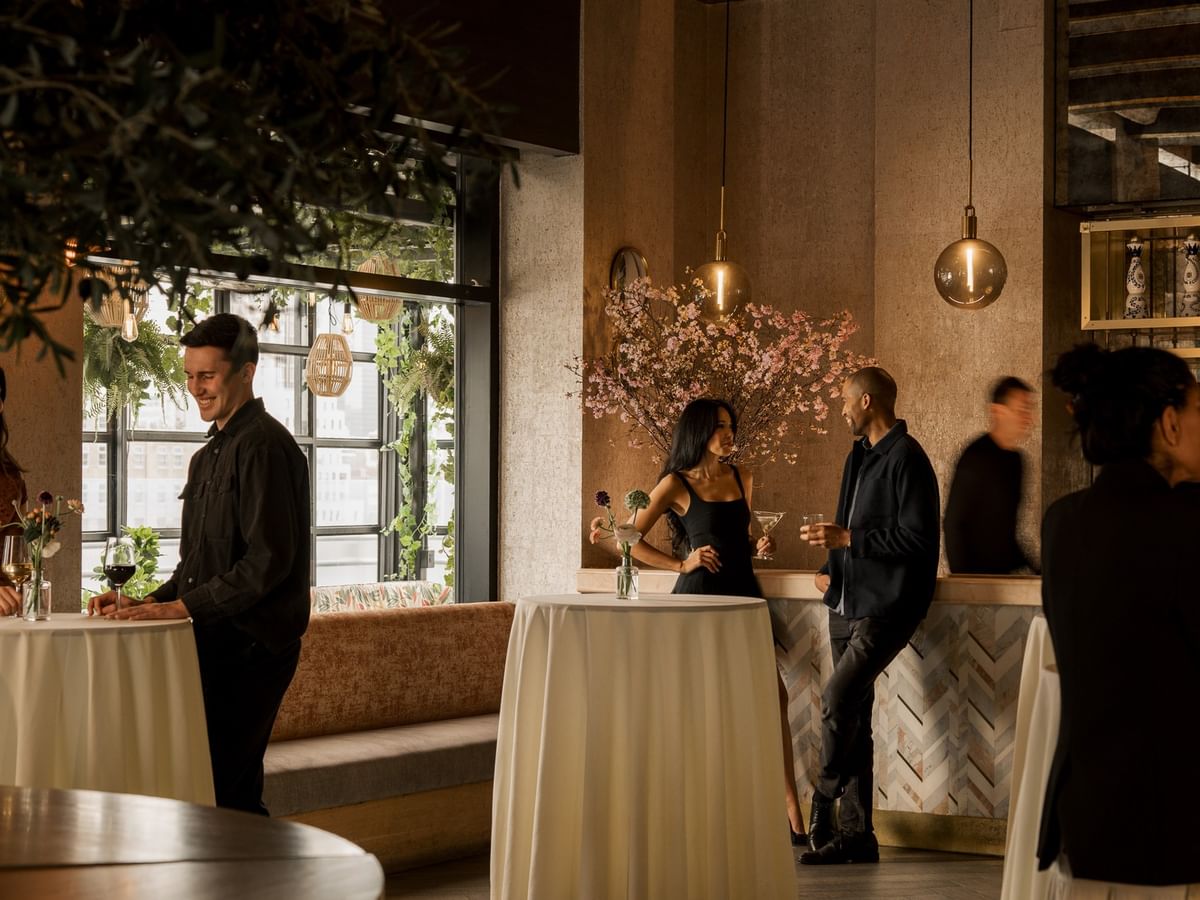 Guests mingling at cocktail tables with floral arrangements in The Loft at Gansevoort Meatpacking NYC - NEW