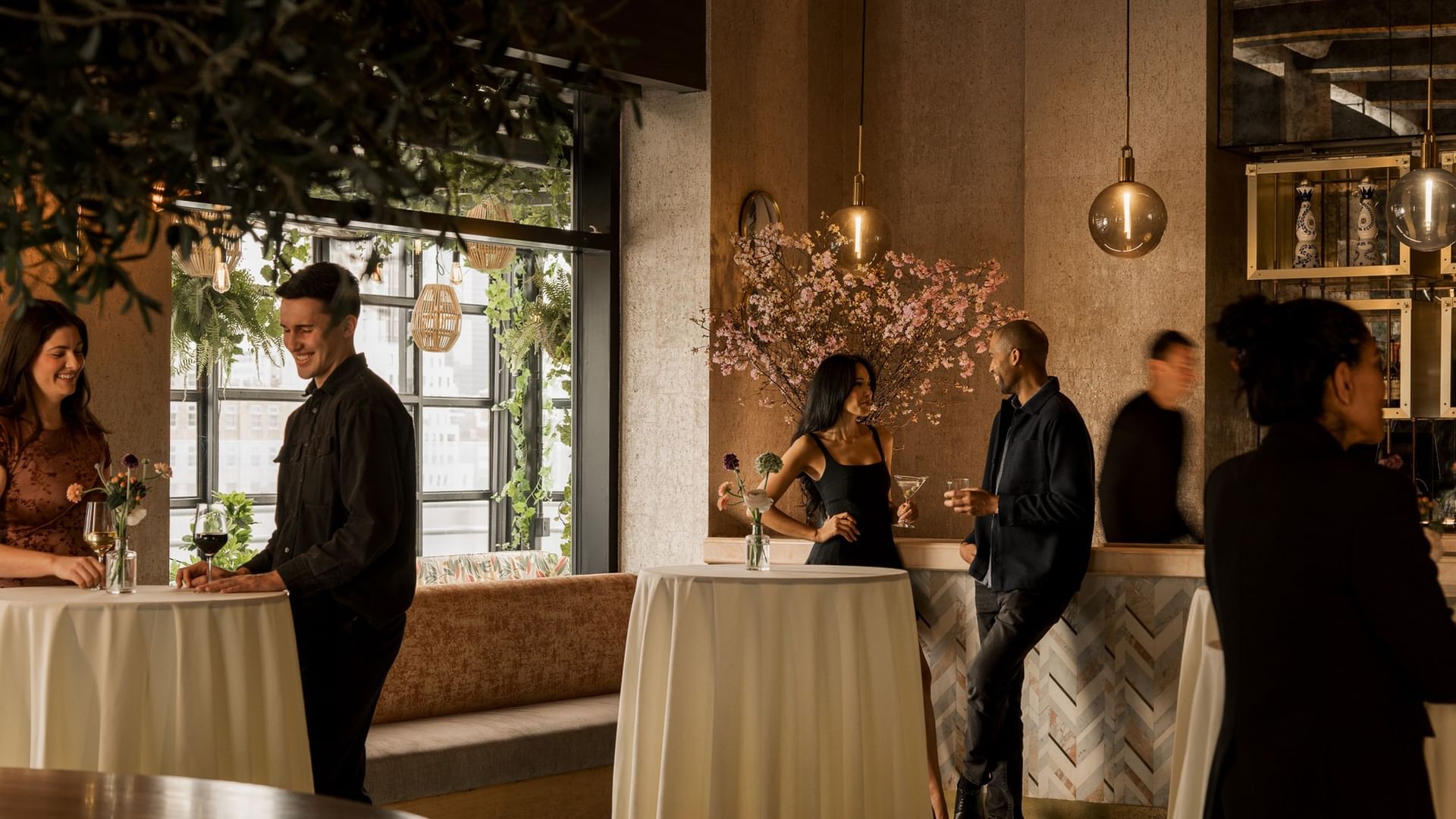 Guests mingling at cocktail tables with floral arrangements in The Loft at Gansevoort Meatpacking NYC - NEW