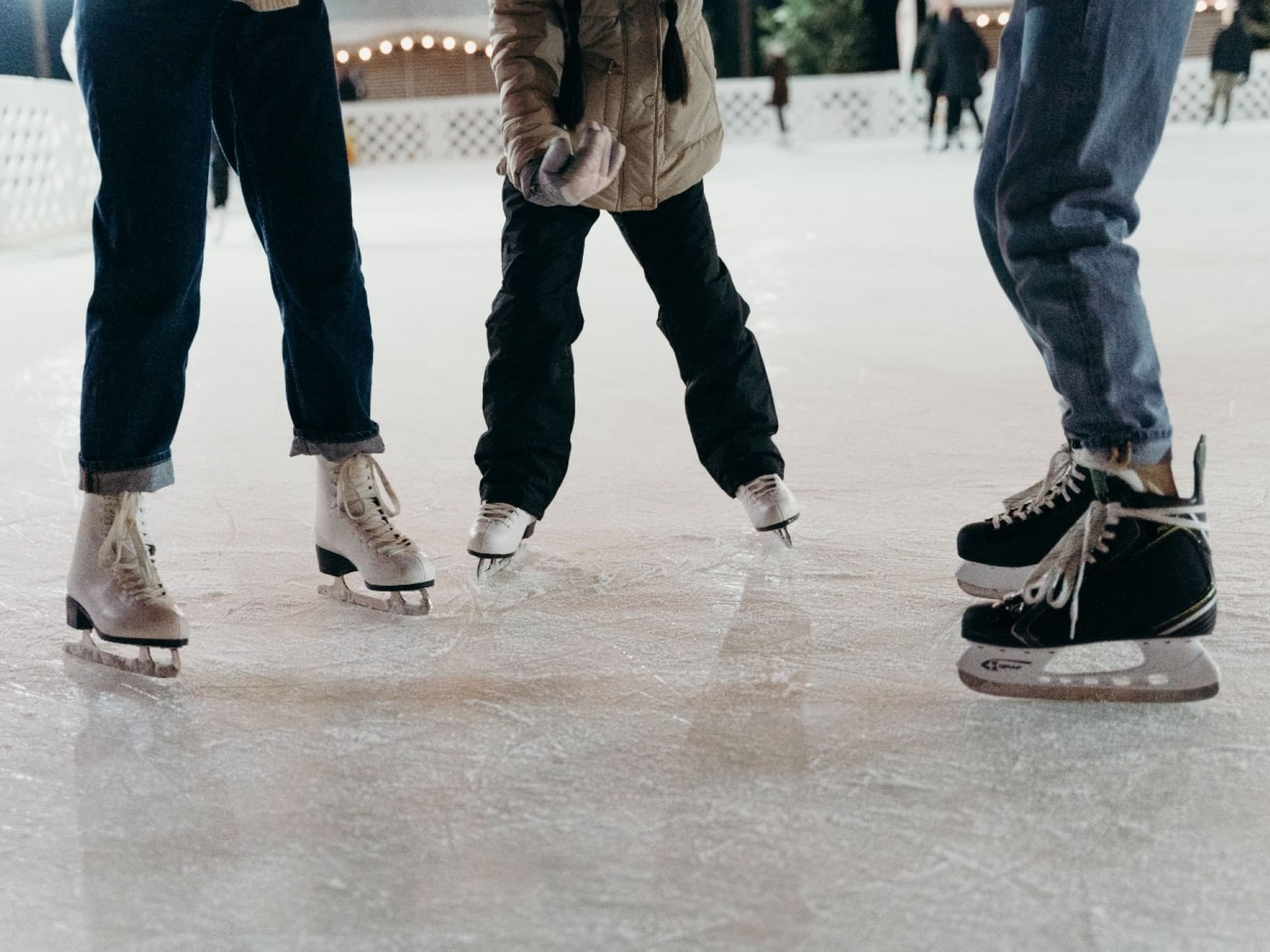 Three people ice skating on an outdoor rink at The Bethel Inn Resort & Suites