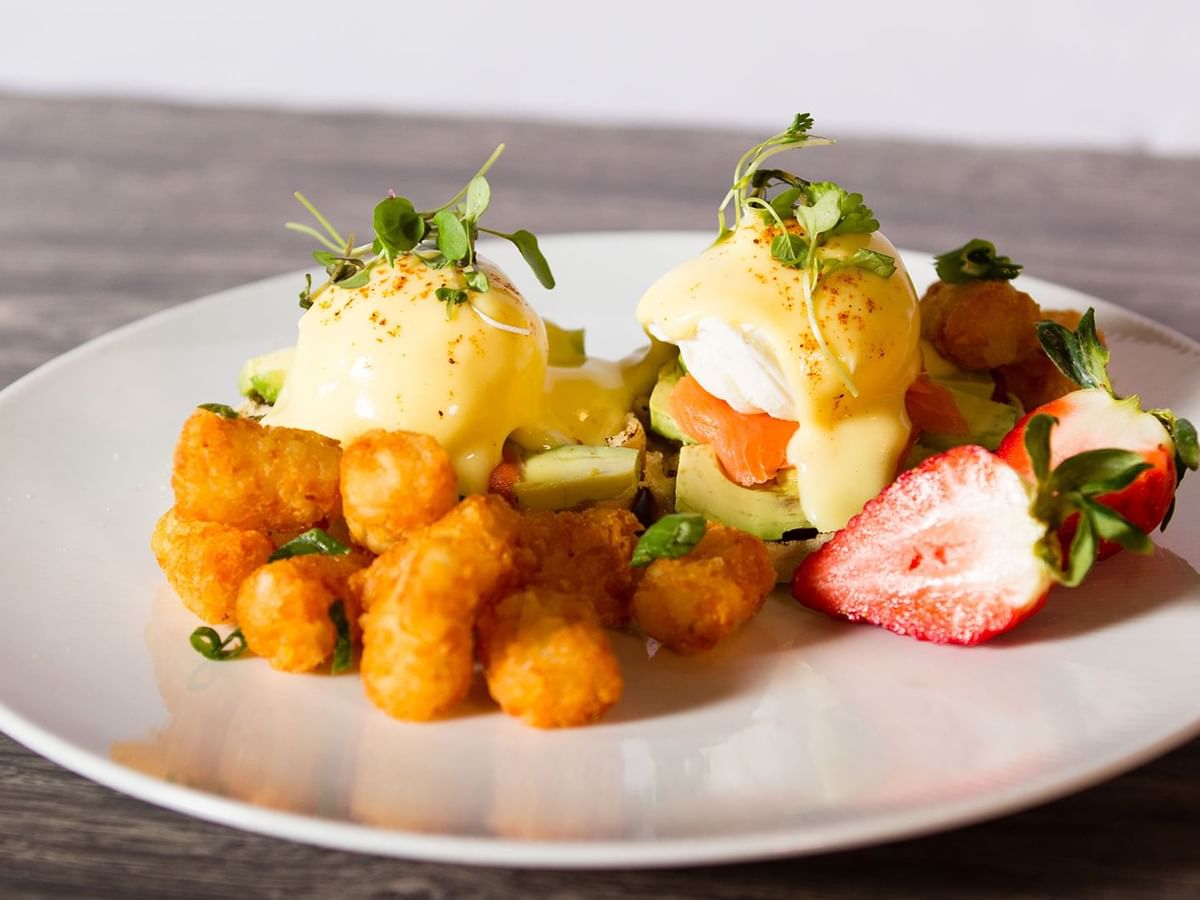 Smoked salmon eggs benedict with fruits and potatoes